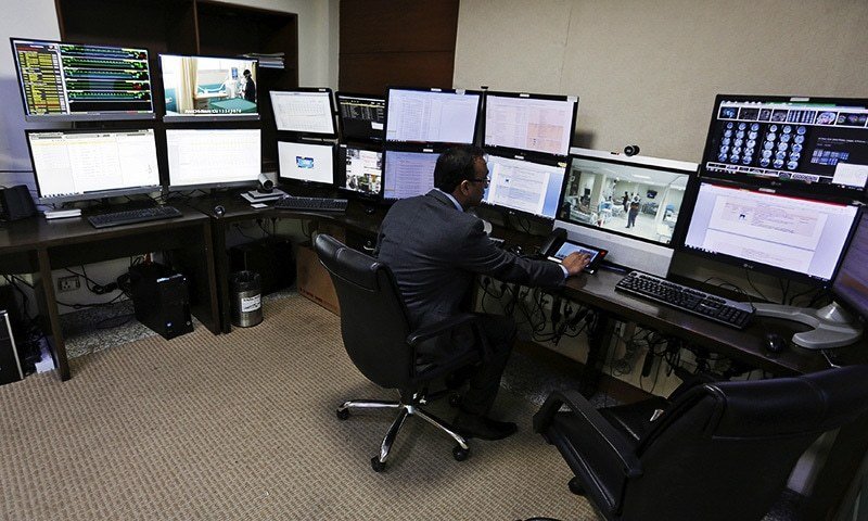 A doctor remotely monitors live footage of patients inside an electronic intensive care unit (eICU
