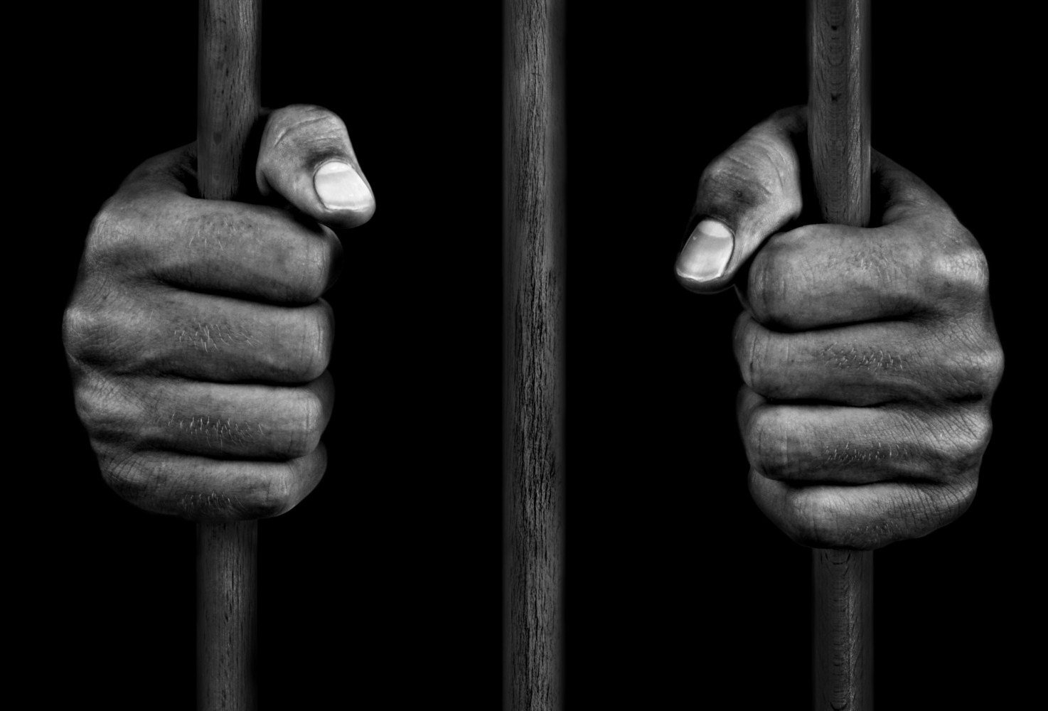 hands of a prisoner on prison bars